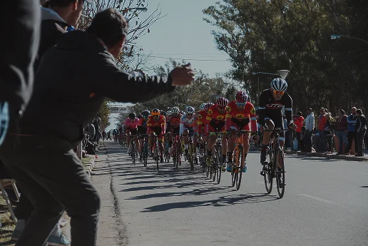 Des cyclistes en peloton lors d'un sprint de compétition, sous le regard des spectateurs qui les acclament depuis le bord de la route par une journée ensoleillée